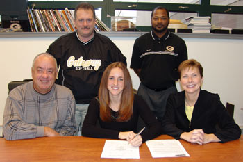 Pam Hartwick (in center, seated), flanked by her parents, Coach Greg Taylor, and AD Terry Smith watch the National Letter of Intent signing.